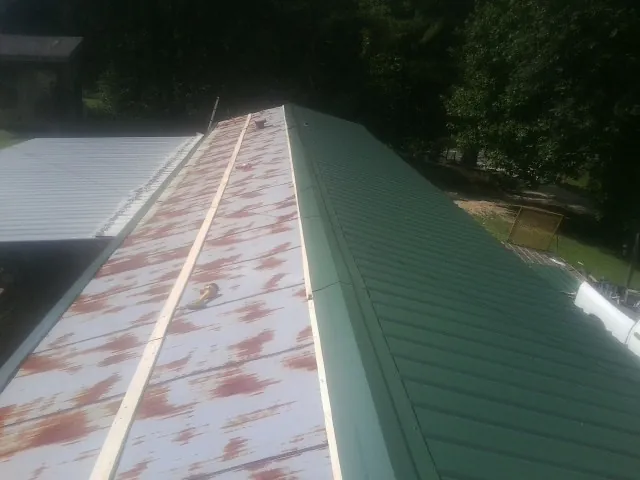 Old rusted panels beside newly installed green metal roofing — Wind Damage Roof Repair by Roofing Brothers in Thornton